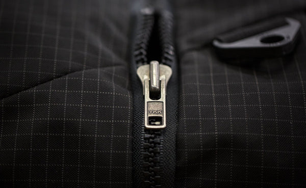 A close shot of the connecting zipper of the main bag and top pocket.